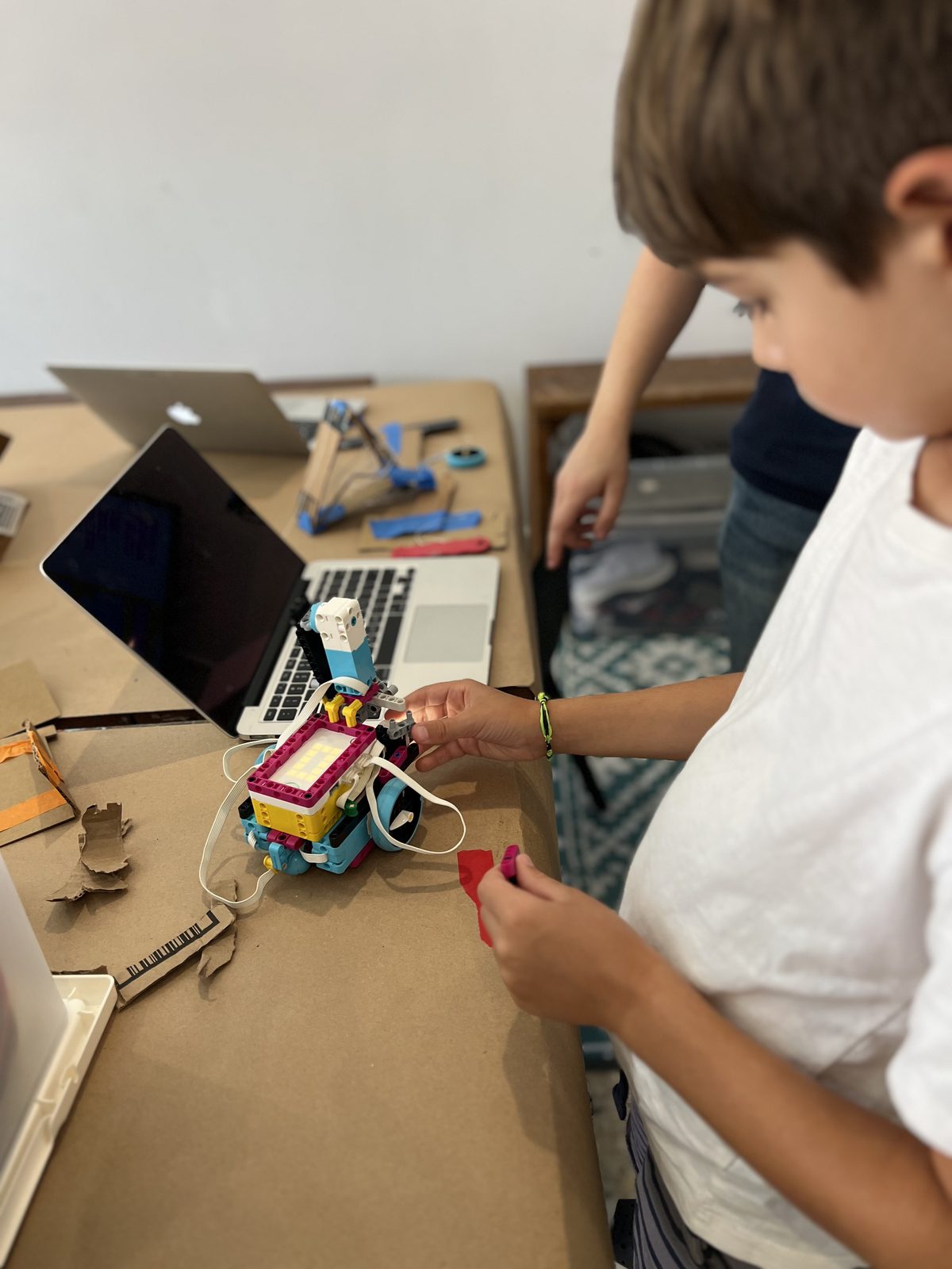 A student building a LEGO robotics project on a workbench